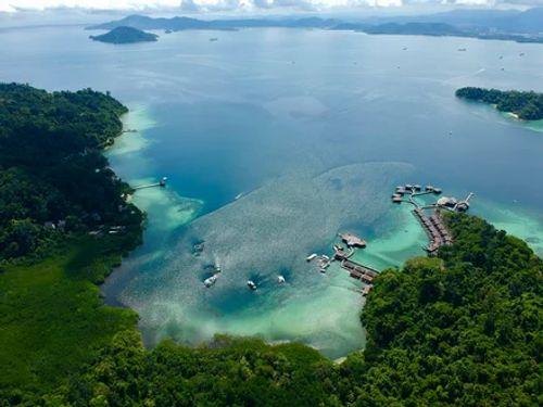 Aerial view of Gaya Island's forested coastline, reefs and stilt jetties